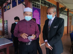 Sulaiman Sulong mengambil peluang meneliti telefon pintar yang bakal diagihkan kepada pelajar di SMK Merchang dan SMK Dato' Awang Jabar.