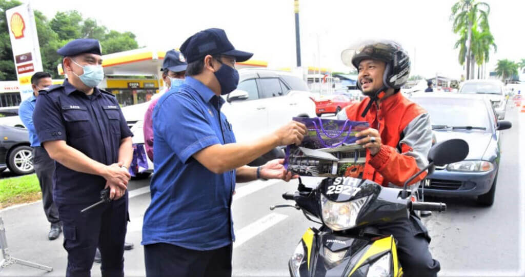 Samsuni (dua dari kiri) diiringi Batholomew (kiri) menyampaikan sumbangan kepada salah seorang pengguna jalan raya.