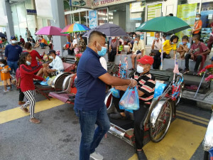 Sukarelawan mengedarkan makanan percuma dan angpow kepada golongan penarik beca dan gelandangan yang terjejas mata pencarian akibat pandemik COVID-19.