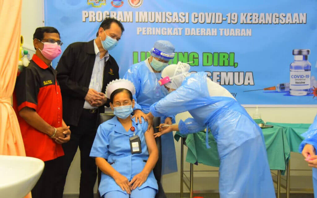 SOKONG... Seorang jururawat (duduk) diberi suntikan vaksin, sambil diperhatikan oleh Noor Hisham (dua kiri).