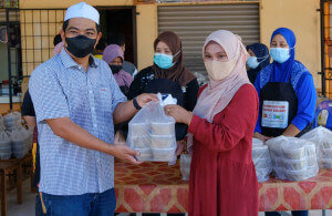 Amir (kiri) menyerahkan bubur lambuk kepada Niswati.