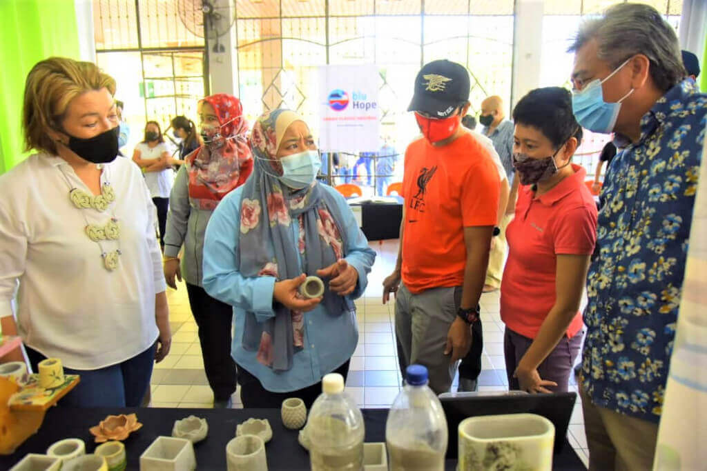 Barangan seperti botol kaca yang telah diproses dijadikan pasu memukau perhatian Noorliza (tiga kiri) sambil bertanyakan sesuatu kepada Jack (kanan).