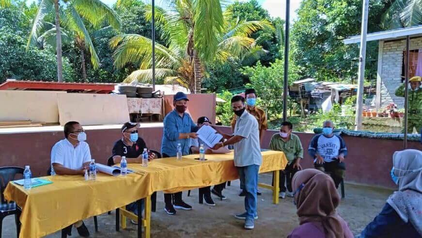 Ketua Kampung Pangi Hujung menyerahkan borang pendaftaran vaksin kepada Pemimpin Pembangunan Masyarakat DUN N.63 Kunak, Hussin Mohd Rais.