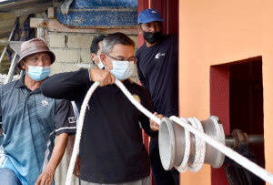 Dr. Azman Ibrahim menggunakan mesin penarik bot selepas merasmikan rumah mesin tarik bot di Kampung Beting Lintang, Besut.