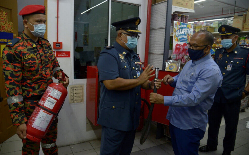 Ismaidi (dua dari kiri) memberi penerangan kepada Bashir mengenai keadaan alat keselamatan kebakaran yang diperiksa.