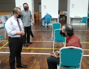 Noor Azmi menyantuni seorang warga emas yang sedang menunggu giliran untuk menerima suntikan vaksin.