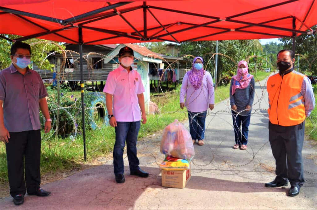 Arthur menyampaikan sumbangan bakul makanan kepada penduduk kampung yang terjejas sambil disaksikan Peter (kiri) dan Andy (kanan).
