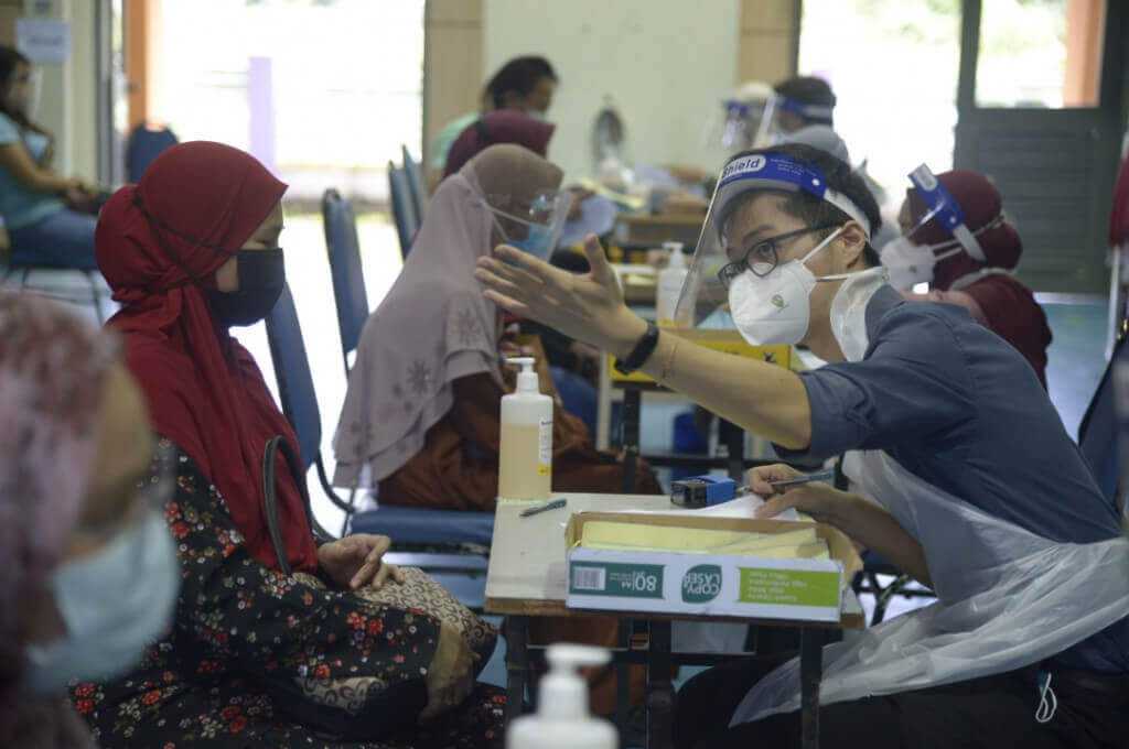 Para petugas sedang mendaftarkan para penerima vaksin yang hadir.