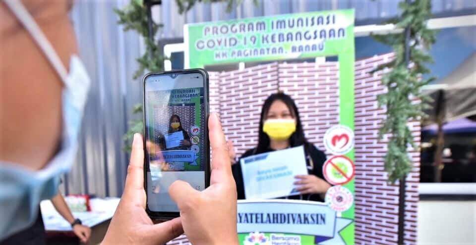 KENANGAN... Antara penduduk Ranau yang merakamkan gambar sejurus selesai menerima suntikan dos pertama vaksin COVID-19.