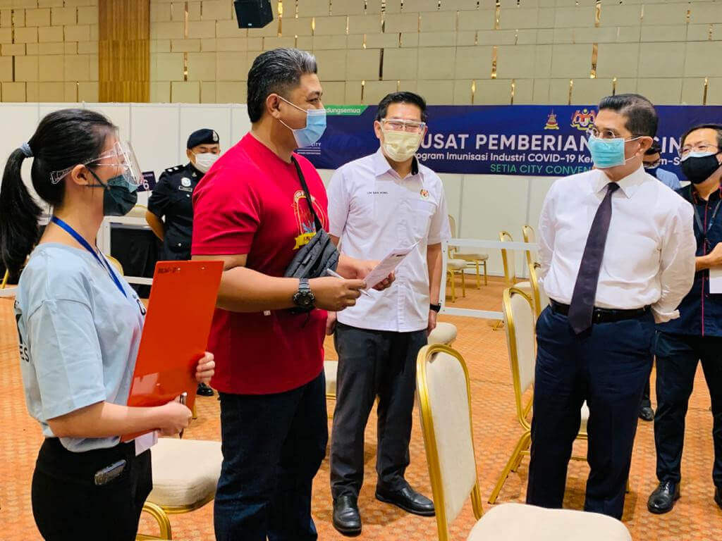 Azmin (kanan) sempat bertanyakan berkenaan kelancaran proses penerimaan vaksin kepada salah seorang penerima suntikan di PPV Setia City Convention Centre.