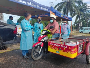 Khairul (kiri) ketika menyerahkan Kotak Rezeki Ummat secara ‘pandu lalu’.