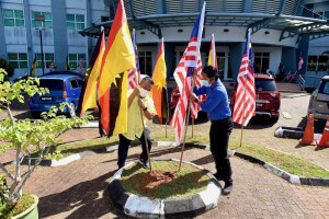 Swady (kiri) bersama Aziz Abdul Rahman memacak bendera negeri Sarawak dan bendera Malaysia.
