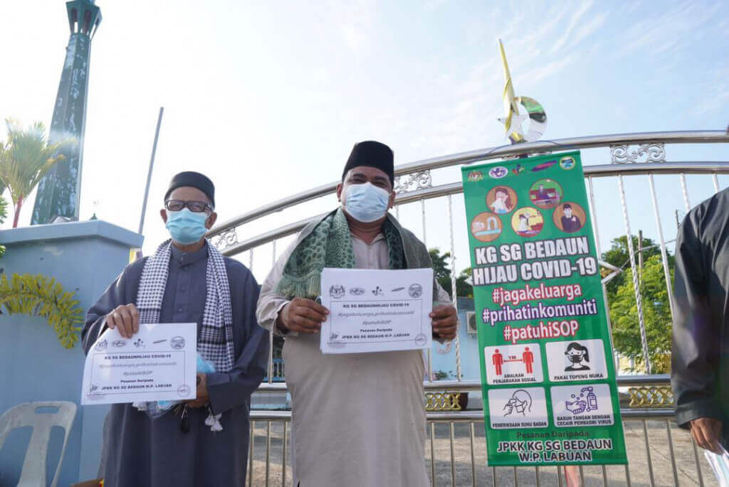 Rosmani (dua dari kiri) bersama salah satu gegantung yang dipasang di Surau kampung itu.