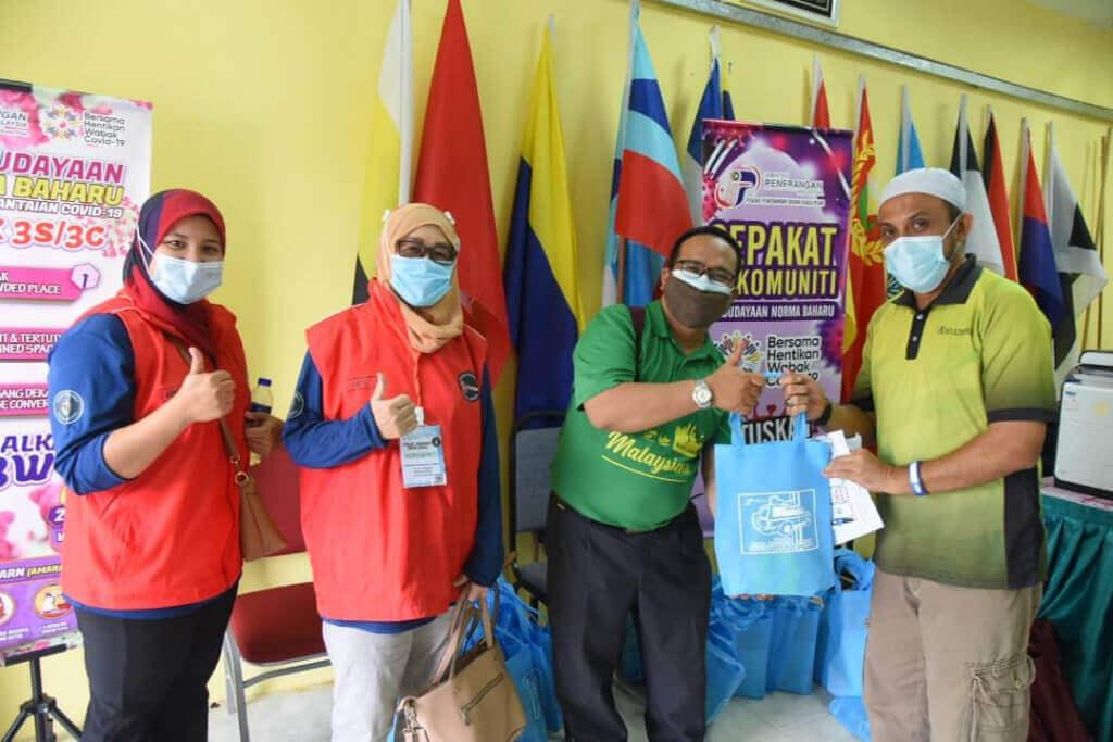 Pegawai Penerangan Daerah Kuala Pilah bersama Sahabat Volunteers menyerahkan cenderhati kepada penerima vaksin.