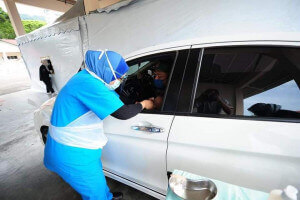Petugas bersiap sedia untuk vaksinasi secara pandu lalu dalam kenderaan.