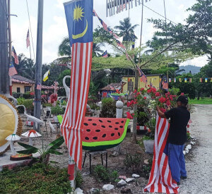 Abu Bakar memasang bendera di halaman rumahnya.