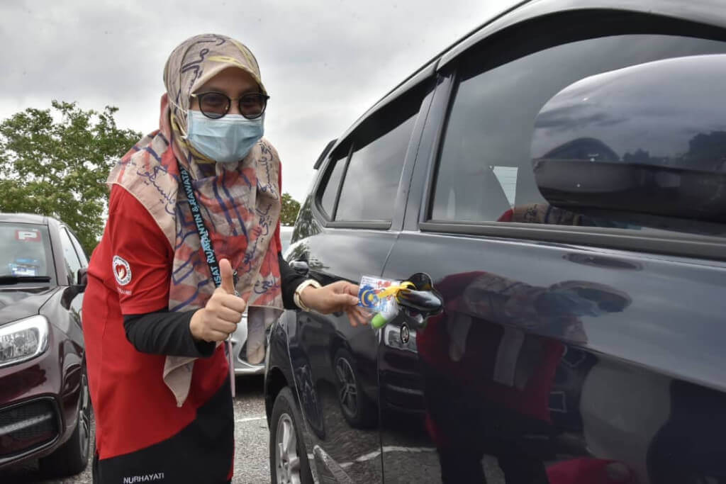 Salah seorang petugas MHPSS sedang memasang kit cenderahati pada salah satu dari 500 buah kenderaan yang menerima kejutan.