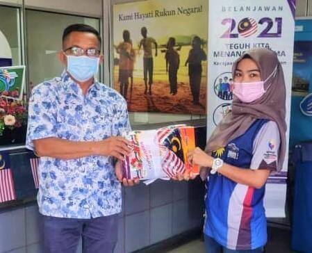 Pembantu Penerangan, Hafidah Japar (kanan) menyampaikan Jalur Gemilang kepada Ketua UPPM Petagas, Latip Jiar sebagai simbolik pengimarahan bulan kebangsaan.