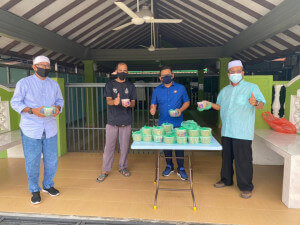 Zaidi Japar (berbaju biru) mengagihkan bubur kepada masyarakat setempat di Mukim Simpang Kanan. 