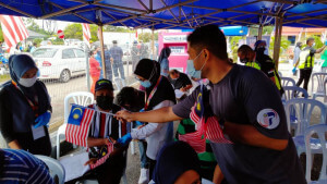 Pejabat Penerangan Daerah Alor Gajah mengedarkan Jalur Gemilang kepada penerima vaksin.