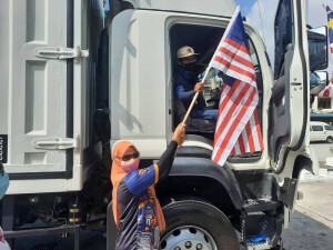 Pegawai Penerangan Daerah Barat Daya mengedar bendera Jalur Gemilang kepada pemandu lori di stesyen minyak Petronas Kg Jawa.