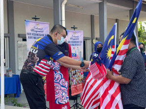 Pegawai Penerangan Daerah Bukit Bintang/Seputeh/Putrajaya, Azri Zainal Abidin menyerahkan Jalur Gemilang kepada warga PUSPEN.