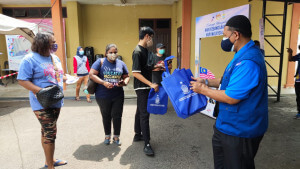 Petugas di PPV mengedarkan beg mengandungi bendera kepada penerima vaksin dalam suasana norma baharu.