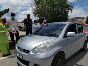 Yang Di Pertua Majlis Daerah Besut, Mohd Rashdan Muda sedang melekatkan Jalur Gemilang pada kenderaan pengguna jalan raya.