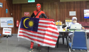 Mohamad Saiful berkostum Spiderman mengibarkan Jalur Gemilang di PPV Dewan Kerian Permai.