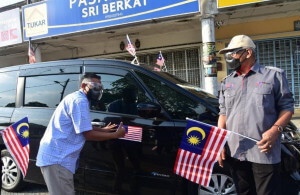 Meor Hezbullah melekatkan magnet Jalur Gemilang pada kenderaan sambil disaksikan Mohd Taib.