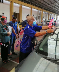 Pengarah ADTEC Taiping, Zulkifle Osman melekatkan Jalur Gemilang mini ke kereta penerima vaksin secara pandu lalu.