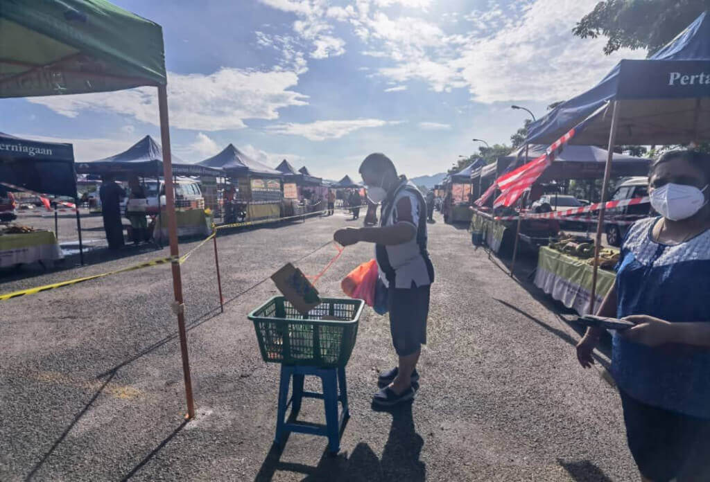 Pengunjung mengambil nombor giliran bagi masuk ke dalam pasar tani bagi membeli barangan keperluan.