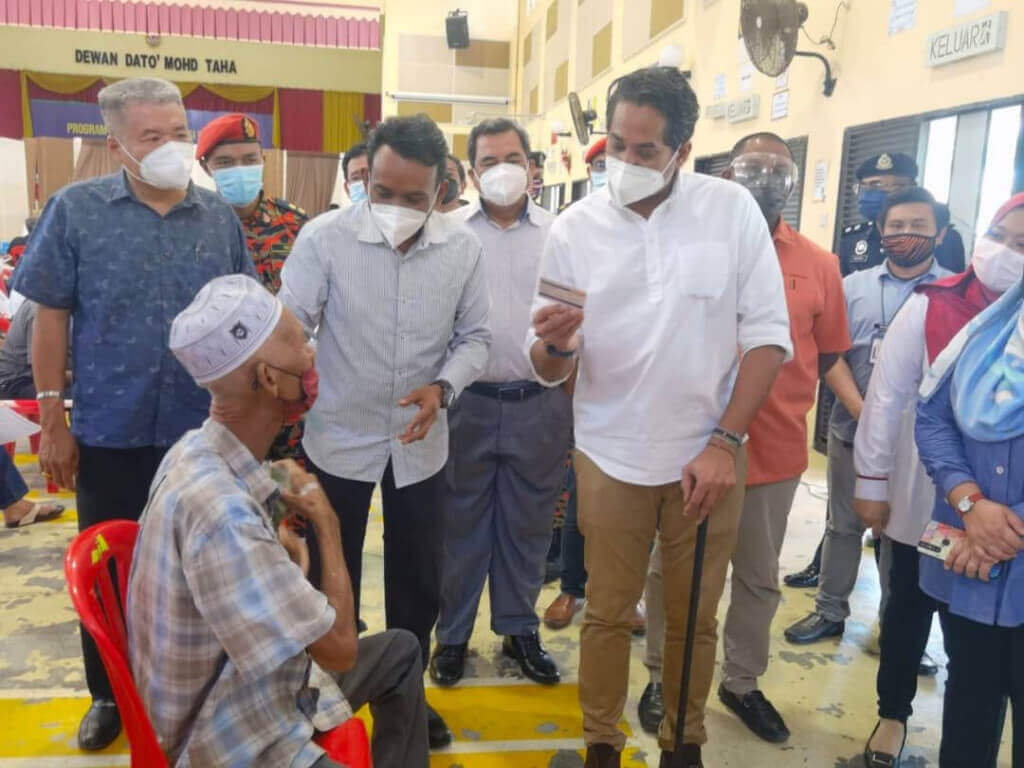 Khairy (kanan) menyantuni warga masyarakat Tampin yang sedang menunggu untuk menerima suntikan vaksin.