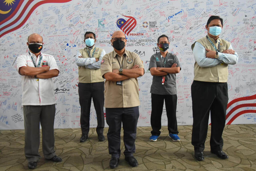 Aminuddin (tengah) ketika sesi bergambar di hadapan Kanvas Solidariti Petugas Barisan Hadapan PKRC Bersepadu MAEPS 2.0.