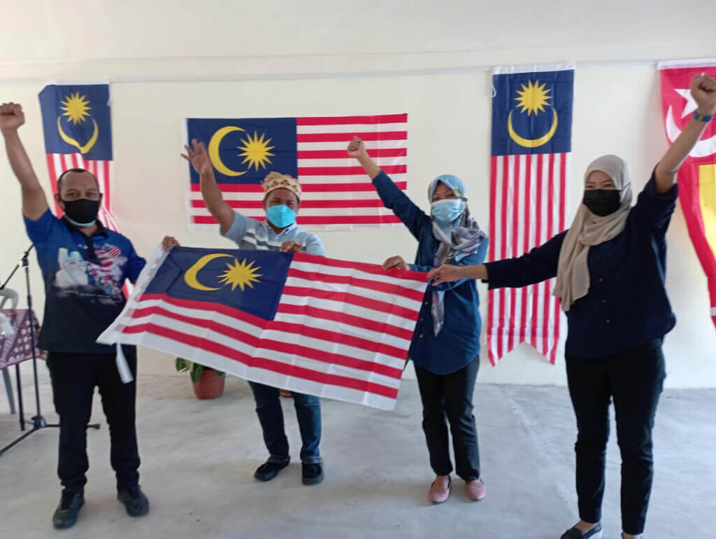 Khairul Shahrizal (kiri) bersama tetamu menyanyikan lagu Jalur Gemilang ketika menjayakan program merdeka@komuniti sempena sambutan Hari Malaysia.