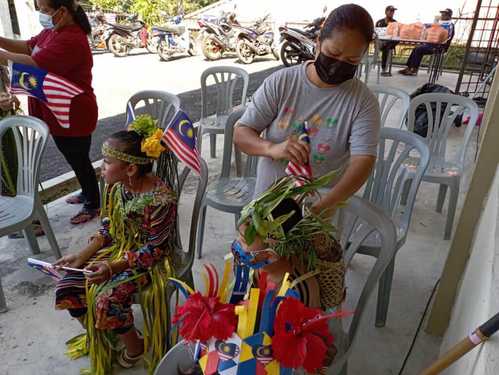 Seorang ibu sedang menyiapkan pakaian beragam anaknya.