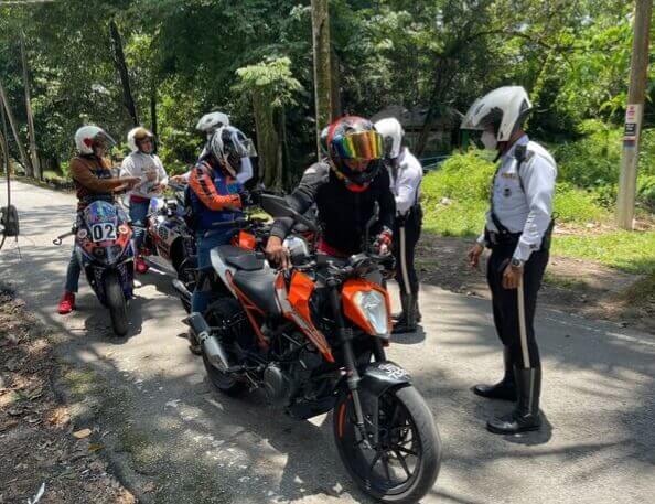 Anggota polis trafik sedang memeriksa penunggang dan motosikal yang berkunjung ke kawasan air terjun Sungai Pisang.