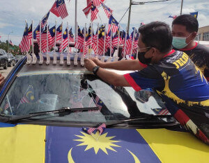 Datuk Jalaludin Alias menampal Jalur Gemilang di kereta Razali.