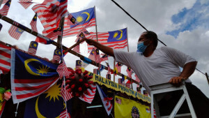 Md Rahim memasang bendera dihalaman rumah.