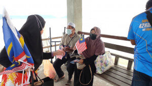 Farhani mengedarkan bendera melalui program IOW di Pulau Aman.