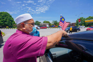 Wan Sukairi melekatkan Jalur Gemilang pada sebuah kenderaan.