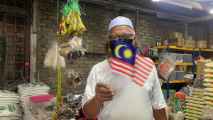 Syed Ahmad memasang beberapa helai Jalur gemilang di kedainya sebagai tanda sokongan kepada kempen Sambutan Hari Kebangsaan dan Hari Malaysia 2021, semalam.