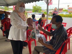 Norhaidah mengedarkan bahan penerbitan dan kit pencegahan COVID-19 kepada penerima vaksin.