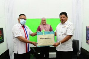 Pengarah Penerangan Negeri Johor Naim Fahmi Amad Tajuddin menyampaikan cenderahati kepada Pengerusi Jawatankuasa Pendidikan, Penerangan, Warisan dan Budaya Negeri Johor Mazlan Bujang.