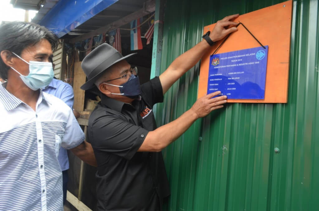 Dr. Ronald menggantungkan papan tanda peserta Projek Khas Perumahan Nelayan (PKPN) di Kg. Kolapis.