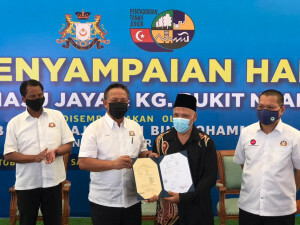 Hasni (dua kiri) menyampaikan geran hak milik kepada Rahamat (dua dari kanan)