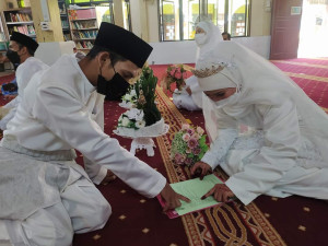 Pasangan mempelai sedang menyemak dokumen semasa majlis akad nikah yang berlangsung di Surau Sekolah Menengah Al-Ahmadiah Al-Ijtimiah, Padang Lalang.